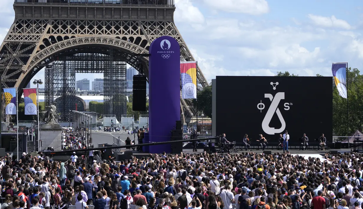 Penonton menyaksikan Woodkid tampil di atas panggung di zona penggemar Olimpiade di Taman Trocadero di depan Menara Eiffel di Paris, Minggu (8/8/2021). Paris akan menjadi tuan rumah Olimpiade Musim Panas berikutnya pada tahun 2024. (AP Photo/Francois Mori)