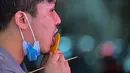 Seorang pelanggan dengan dalgona, permen gula renyah yang ditampilkan dalam serial Netflix Squid Game, di Shanghai pada 12 Oktober 2021. Meski Netflix diblokir pemerintah China, tetapi serial Netflix Squid Game sukses meraih popularitas di Negeri Tirai Bambu itu. (Hector RETAMAL/AFP)