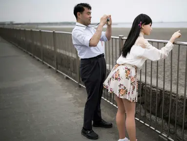 Ahli fisioterapi, Masayuki Ozaki mengambil gambar boneka seks silikon miliknya di Teluk Yuku, Jepang (9/6). Masayuki Ozaki, 45 tahun, adalah seorang pria asal Jepang yang mengaku mencintai boneka seksnya yang bernama Mayu. (AFP photo/Benrouz Mehri)