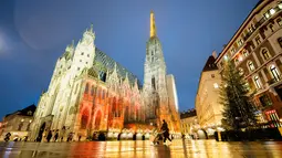 Orang-orang berjalan melewati Pasar Natal "Christkindlmarkt" Wina yang ditutup, dan Katedral St Stephen di Wina, Austria, Senin (22/11/2021). Austria kembali menerapkan lockdown penuh untuk mengekang infeksi Covid-19 menyebar ke seluruh Eropa. (GEORG HOCHMUTH / APA / AFP)