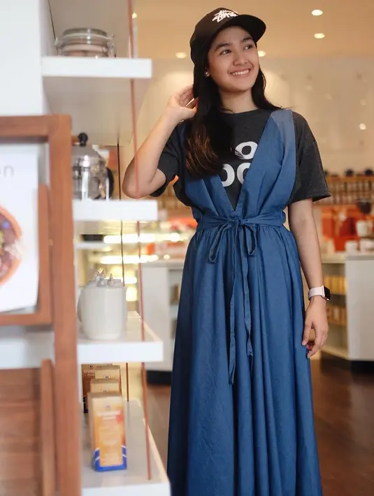 Untuk yang satu ini, masih dengan kaus dan topi hitam. Namun Syifa memadukannya dengan overall dress yang modelnya cute banget. (Instagram/cutsyifaa)