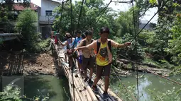 Sejumlah pelajar melintasi Kali Angke menggunakan jembatan rapuh di Kampung Cantiga, Petir, Cipondoh, Tangerang, Rabu (2/9/2015). Jembatan berusia lima tahun tersebut menghubungkan Cipondoh dan Kembangan, Jakarta. (Liputan6.com/Gempur M Surya)