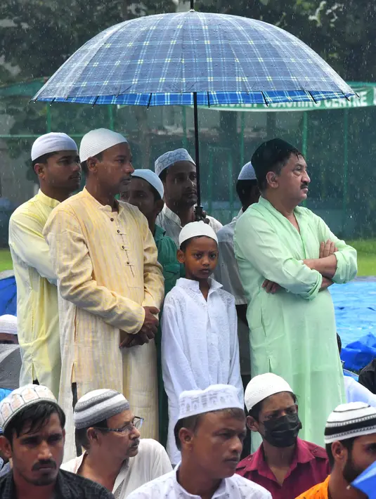 Umat ​​Muslim berlindung dari hujan di bawah payung saat salat Idul Adha di Guwahati, India pada 29 Juni 2023.
(Biju BORO/AFP)