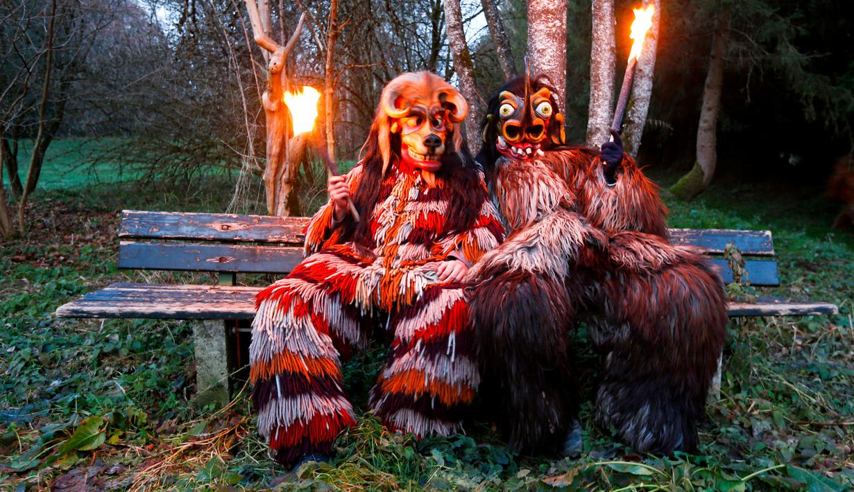 Sejumlah peserta mengenakan kostum iblis duduk sambil memegang obor bersiap mengikuti parade tardisional Perchtenlauf di Osterseeon dekat Munchen, Jerman (17/12). Tradisi ritual Pagan ini telah berusia 1.500 tahun (Reuters/Michaela Rehle)