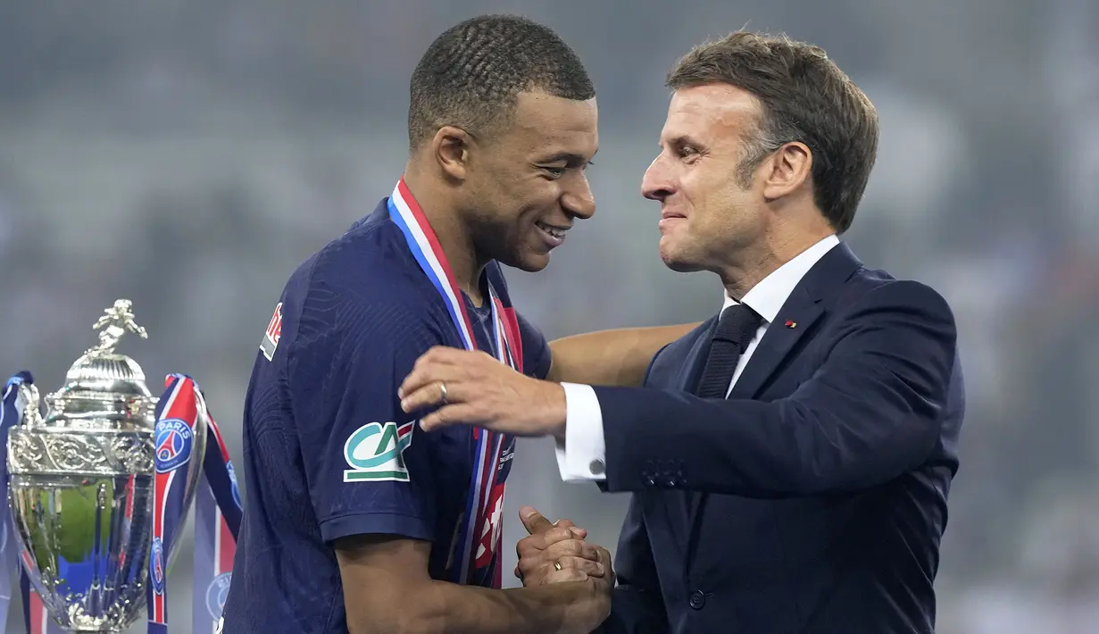 Pemain PSG, Kylian Mbappe (kiri) bersalaman dengan Presiden Prancis, Emmanuel Macron saat upacara penyerahan trofi Coupe De France 2023/2024 di Stade Pierre-Mauroy, Villeneuve-d'Ascq, Prancis, Minggu (26/05/2024) WIB. PSG menang dengan skor 2-1 atas Olympique Lyon pada babak final. (AP Photo/Michel Euler)