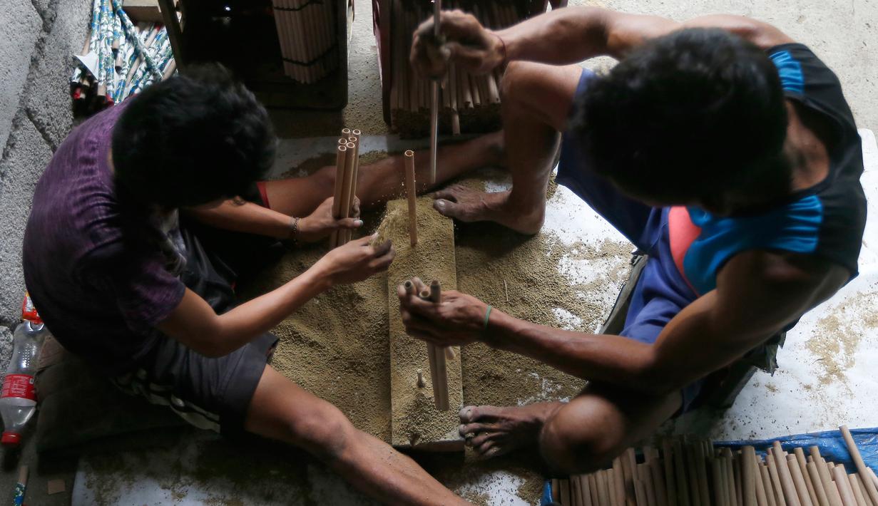 Pekerja membuat tabung pembungkus kembang api di sebuah gubuk, provinsi Bulacan, utara Manila, Rabu (27/12). Seperti banyak negara di Asia, warga Filipina juga akan merayakan malam pergantian tahun dengan kembang api tradisional. (AP/Bullit Marquez)