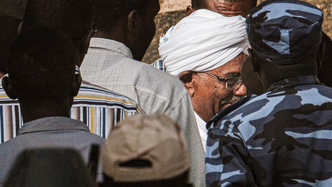 Mantan Presiden Sudan, Omar al-Bashir, dikawal setelah menghadap jaksa dalam penyelidikan korupsi di ibu kota Khartoum, Minggu (16/6/2019). Bashi ditahan sejak militer menyingkirkannya dari kekuasaan April lalu, di tengah demonstrasi menentang kepemimpinannya selama 30 tahun. (Yasuyoshi CHIBA/AFP)