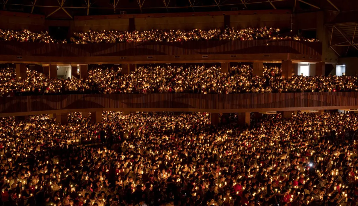 Ribuan jemaat yang hadir menyalakan lilin saat ibadah malam Natal berlangsung. (Juni KRISWANTO/AFP)