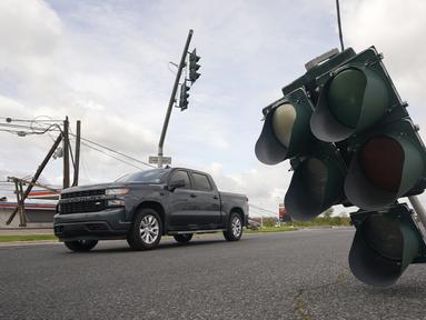 Kendaraan melintasi lampu lalu lintas yang tergantung di kabel setelah terjangan Badai Ida di LaPlace, Louisiana, Senin (30/8/2021). Badai Ida ini sebagai salah satu badai paling kuat yang pernah melanda Amerika Serikat. (AP Photo/Steve Helber)