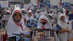 Aktivis konservasi hewan mengenakan pakaian hiu dan membawa poster saat menggelar aksinya di dekat restoran di Hong Kong (10/6). Para aktivis memprotes penjualan sup sirip ikan hiu yang masih banyak di Hong Kong. (AP Photo / Kin Cheung)