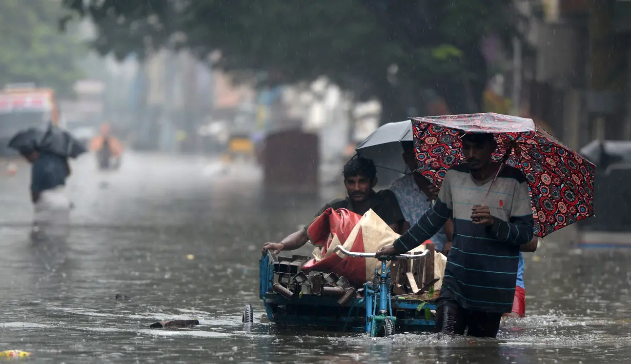 Orang-orang mengarungi jalan yang banjir setelah hujan lebat di Chennai, India (8/11/2021). Chennai dilanda Curah Hujan Terberat Sejak 2015,  Pihak berwenang Keluarkan Peringatan Banjir. (AFP/Arun Sankar)