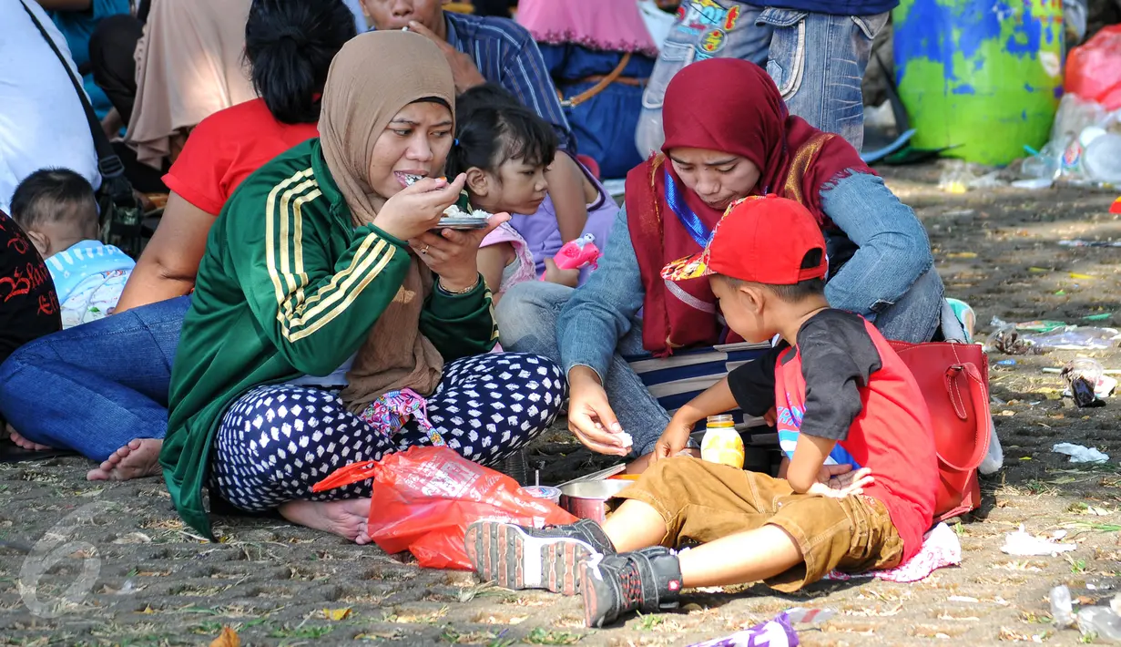 Meski hanya beralaskan tikar diatas rumput, namun kecerian dan kekeluargaan sangat terasa saat makan bersama di area wisata Taman Mini Indonesia Indah, Jakarta, Minggu (19/07/2015). (Liputan6.com/Yoppy Renato)