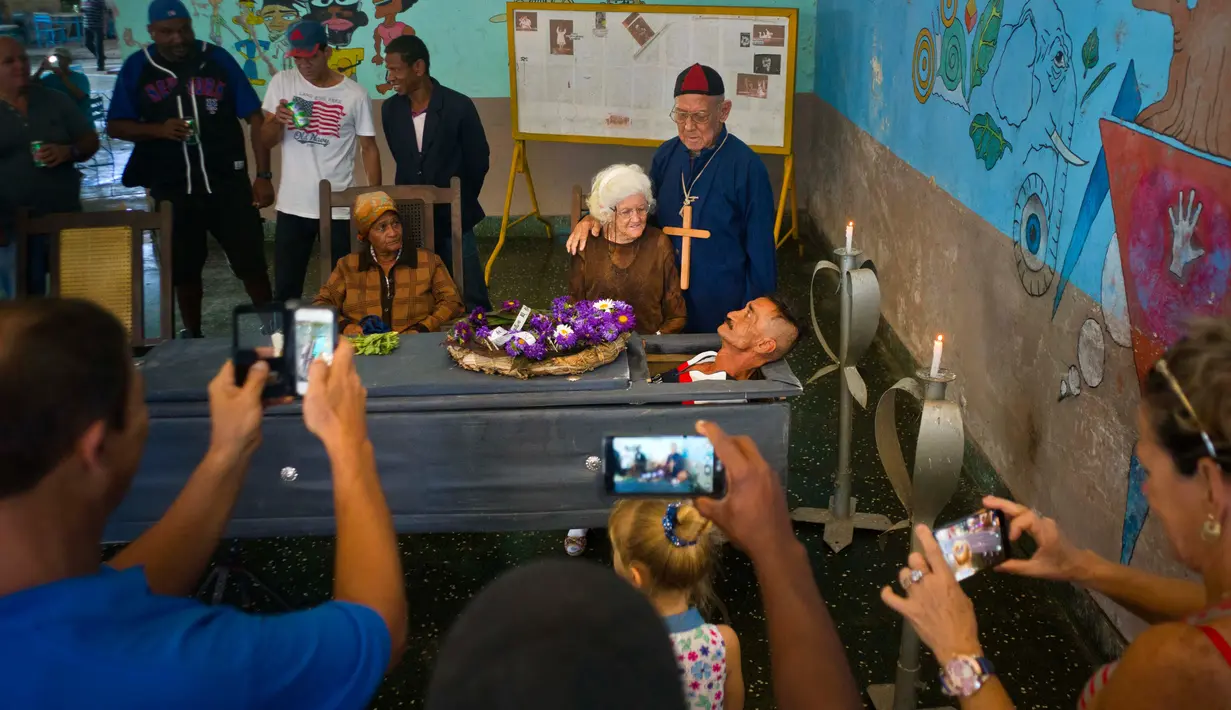 Pria bernama Divaldo Aguiar berbaring di dalam peti saat melakukan festival Burial of Pachencho di Santiago de Las Vegas, Kuba (5/2). Perayaan ini merupakan tardisi masyarakat setempat yang digelar setiap tangggal 5 Februari. (AP Photo/Ramon Espinosa)
