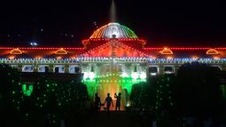 Siluet orang-orang dengan latar belakang Pengadilan Tinggi Allahabad yang diterangi pada malam Hari Kemerdekaan India di Prayagraj pada tanggal 14 Agustus 2023. (Photo by Sanjay KANOJIA / AFP)