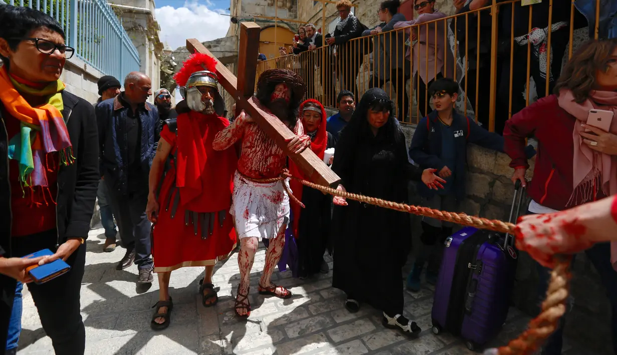 Seorang aktor berpakaian seperti Yesus Kristus memanggul salib saat melakukan prosesi Jalan Salib menyusuri Via Dolorosa menuju Gereja Makam Suci di Kota Tua Yerusalem, Jumat (19/4). Dalam aksi tersebut digambarkan Yesus Kristus didera dan disiksa oleh tentara Romawi. (AP Photo/Ariel Schalit)