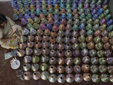 Perajin mewarnai pot minyak tembikar atau diyas menjelang Diwali, festival lampu Hindu, di sebuah lokakarya di Hyderabad (4/11/2020). Diwali yang kadang disebut Dipavali, Deepawali atau Deepavali adalah festival lampu paling terkenal yang ditunggu tiap tahunnya di India. (AFP Photo/Noah Seelam)