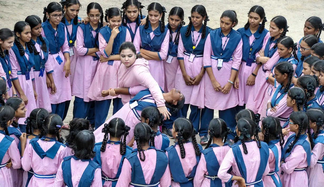 Sejumlah siswi melihat juara karate internasional Muslim India, Syeda Falak menunjukkan teknik bela diri kepada seorang siswi di Telangana Minorities Residential Girls School di Hyderabad, India (17/6). (AFP Photo/Noah Seelam)