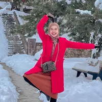 Ria Ricis memakai outerwear mantel warna merah untuk menghangatkan tubuhnya di tengah salju sekaligus menjadi gaya pernyataan yang bold. (Foto: Instagram @teukuryantr)