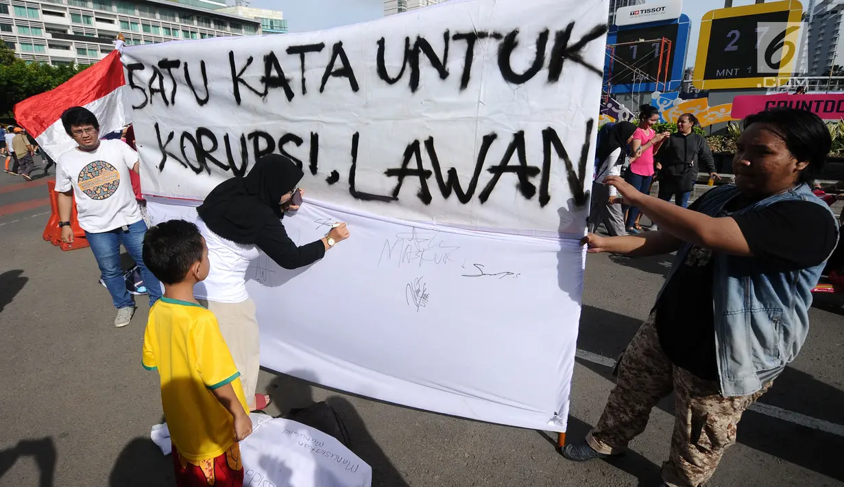 Aktivis mengajak warga menandatangani spanduk dukungan anti korupsi saat Hari Bebas Kendaraan di kawasan Bundaran HI, Jakarta, Minggu (10/12). Ajakan ini untuk memperingati Hari Antikorupsi 2017, 9 Desember. (Liputan6.com/Helmi Fithriansyah)