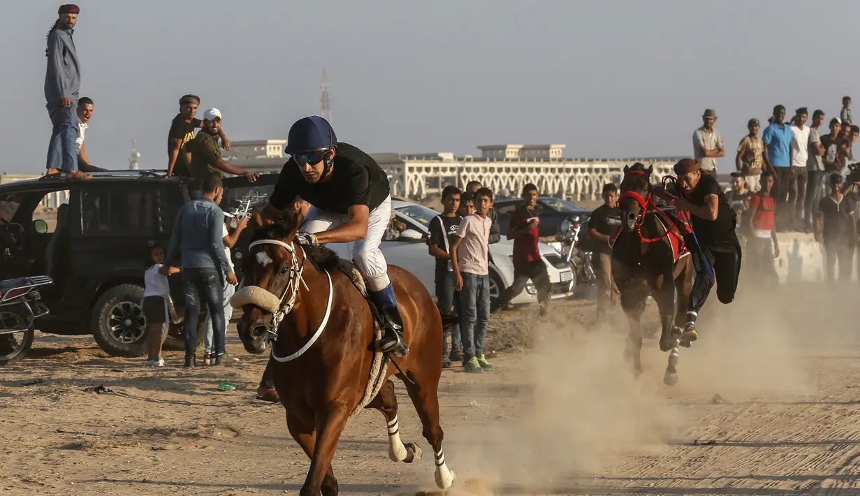 Sejumlah joki memacu kudanya saat bersaing dalam balap kuda di Rafah, Jalur Gaza, Palestina, Selasa (10/9/2019). Balapan kuda tradisional Palestina tersebut digelar di bekas lokasi bandara Jalur Gaza yang telah hancur. (AFP Photo/Said Khatib)