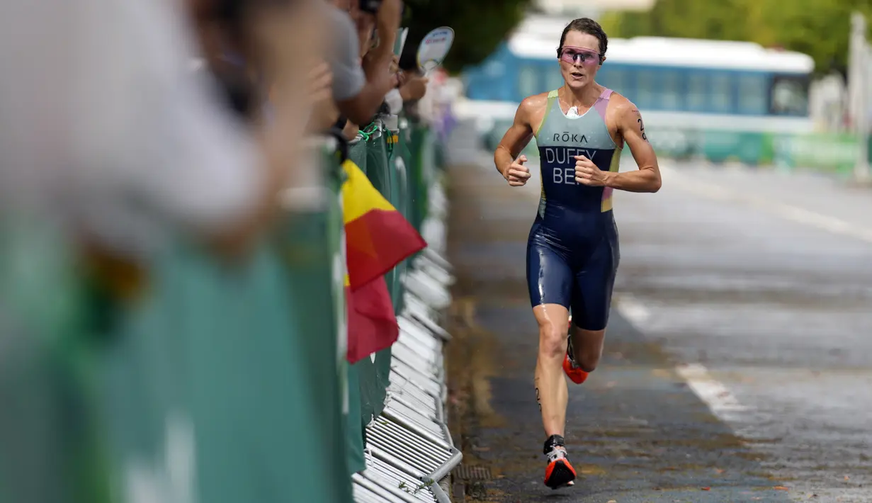 Flora Duffy dari Bermuda berlari di dekat beberapa penonton di sepanjang jalan selama kompetisi triathlon nomor individu putri Olimpiade Tokyo 2020 di Odaiba Marine Park, Selasa (27/7/2021). Flora Duffy menjadi penyumbang medali emas untuk negara berpenduduk 60 ribu orang itu. (AP/Eugene Hoshiko)