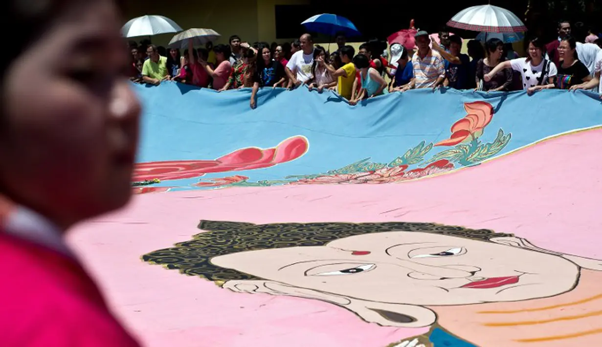 Sebuah spanduk bergambar Buddha dibentangkan dan diarak oleh warga yang ikut perayaan Waisak, Myanmar, Selasa (13/05/2014) (AFP Photo/Manan Vatsyayana)