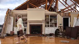 Jenny Bullard membawa sepasang sepatu dari rumahnya yang rusak akibat badai besar yang menghantam Negara Bagian Georgia, Amerika Serikat, Minggu (22/1). Puluhan orang mengalami luka-luka dan sedang dilarikan ke rumah sakit terdekat (AP Photo/Branden Camp)