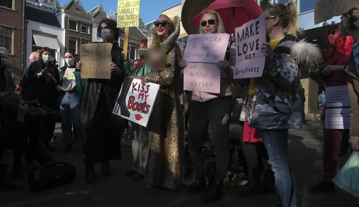 Para pekerja seks membawa plakat memprotes perlakuan dan stigma yang tidak setara selama demonstrasi di Den Haag, Belanda, Selasa (2/3/2021). Mereka berdemonstrasi di luar parlemen dalam protes terhadap penguncian keras virus corona oleh pemerintah. (AP Photo/Patrick Post)