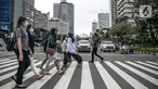 Orang-orang menyeberang jalan dengan latar belakang gedung perkantoran di kawasan Sudirman, Jakarta, Rabu (16/12/2020). Pemprov DKI Jakarta akan mengikuti arahan Wakil Ketua Komite Penanganan Covid-19 Luhut Binsar Pandjaitan terkait pengetatan work from home (WFH). (Liputan6.com/Faizal Fanani)