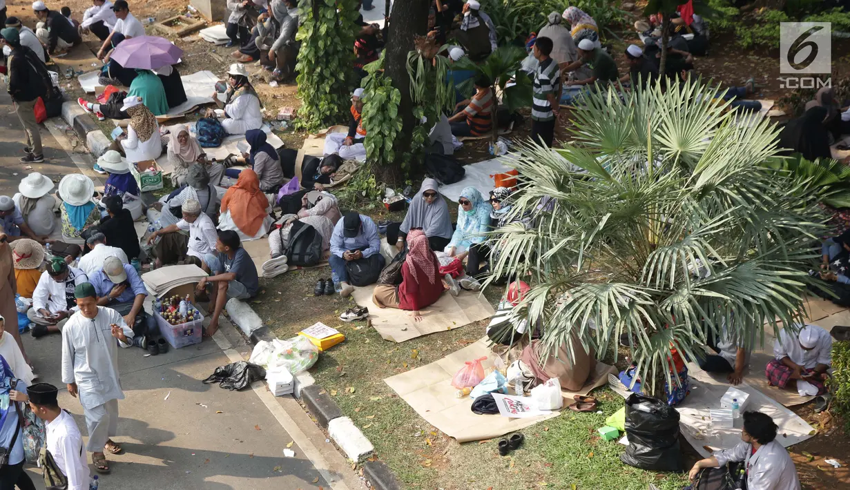 Massa aksi duduk-duduk beristirahat di taman pembatas Jalan Medan Merdeka Barat, Jakarta, Kamis (27/6/2019). Massa aksi berkumpul terkait pelaksanaan sidang putusan perselisihan hasil Pilpres 2019 di Gedung Mahkamah Konstitusi. (Liputan6.com/Helmi Fithriansyah)
