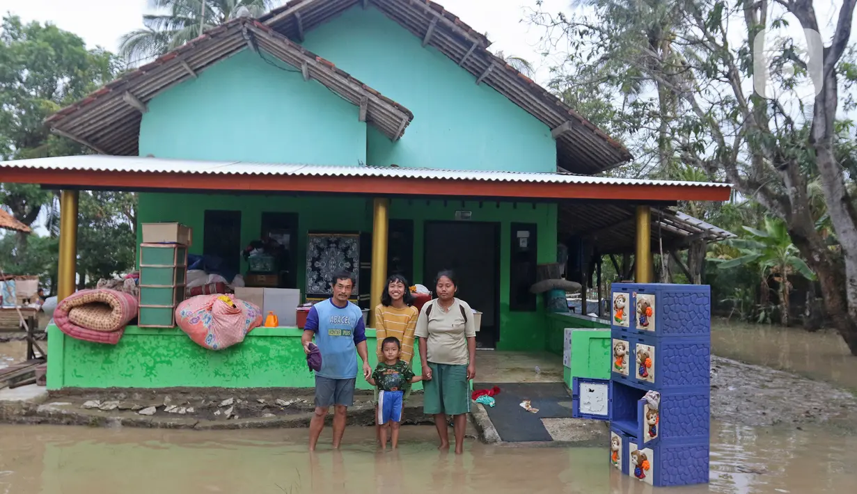 Keluarga Pak Unang berpose di depan kediamannya Desa Sumber Urip Pebayuran, Kabupaten Bekasi, Jawa Barat, Senin (22/2/2021). Banjir merenda keluarga tersebut merapikan barang-barang dan bersihkan rumah yang sudah surut. (Liputan6.com/Herman Zakharia)