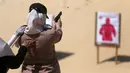 Seorang wanita Palestina memegang pistol saat melepas tembakan ke target sasaran selama mengikuti pelatihan dengan anggota perlindungan dan keamanan Hamas di Khan Younis di Jalur Gaza, Minggu (24/7). (REUTERS/ Ibraheem Abu Mustafa)