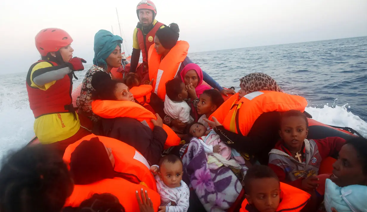 Sejumlah wanita dan balita terombang-ambing di kapal kayu yang disesaki puluhan imigran, di lepas panti Libya, Laut Mediterania, Senin (29/8). Penjaga pantai Italia berhasil menyelamatkan 6.500 imigran dari Eritrea dan Somalia. (REUTERS/Giorgos Moutafis)