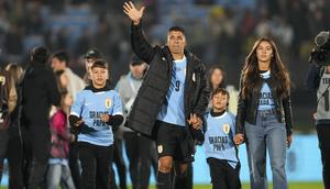 Pemain Uruguay, Luis Suarez (tengah) bersama ketiga anaknya melambaikan tangan kepada para penonton saat acara perpisahannya dengan Timnas Uruguay sebelum laga kualifikasi Piala Dunia 2026 melawan Paraguay yang berlangsung di Stadion Centenario, Montevideo, Uruguay, Sabtu (07/09/2024) WIB. (AFP/Dante Fernandez)