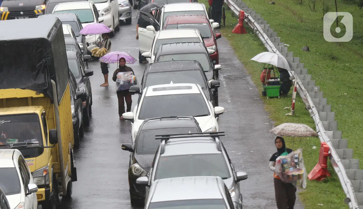 Sejumlah pedagang asongan menawarkan dagangan kepada pengendara di jalan tol Jagorawi yang sedang menanti waktu buka tutup jalur menuju kawasan wisata puncak, Bogor, Jawa Barat, Sabtu (31/10/2020). (Liputan6.com/Helmi Fithriansyah)