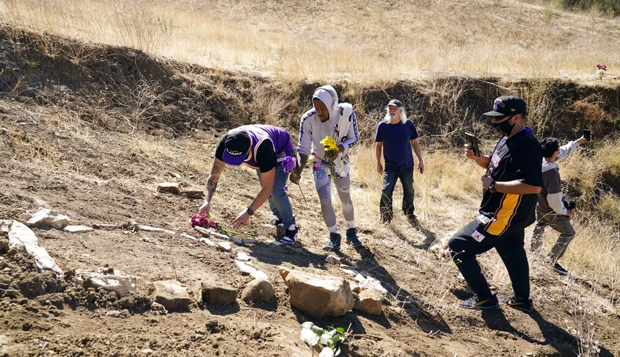 Para simpatisan meletakkan bunga untuk menghormati Kobe Bryant di lokasi kecelakaan helikopter yang menewaskan Bryant, putrinya Gianna, dan tujuh orang lainnya satu tahun lalu di Calabasas, California, Amerika Serikat, Selasa (26/1/2021). (AP Photo/Marcio Jose Sanchez)