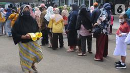 Seorang ibu melintasi antrean warga saat operasi pasar minyak goreng murah di Kantor Kecamatan Pamulang, Tangerang Selatan, Selasa (11/1/20222). Minyak murah itu dijual dengan harga Rp14 ribu per liter dan warga hanya diperbolehkan membeli sebanyak 2 liter. (merdeka.com/Arie Basuki)