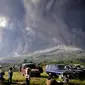 Orang-orang menyaksikan Gunung Sinabung memuntahkan material vulkanik saat meletus di Karo, Sumatera Utara, Selasa (2/3/2021). Gunung berapi setinggi 2.600 meter (8.530 kaki) itu meletus Selasa, mengirimkan material vulkanik beberapa ribu meter ke langit. (AP Photo)