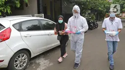 Petugas KPPS menggunakan hazmat sebelum menuju rumah pemilih di kawasan Depok, Rabu (9/12/2020). Petugas jemput bola atau mengambil suara dari warga yang diduga terpapar COVID-19 atau sedang menjalani isolasi mandiri di salah satu perumahan dalam Pilkada Depok 2020. (Liputan6.com/Herman Zakharia)