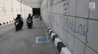 Pengendara motor melewati coretan di dinding underpass atau lintas bawah Matraman, Jakarta Selatan, Rabu (2/5). Corat-coret tersebut terpampang jelas ketika melintas dari arah Jalan Tambak menuju kawasan Pramuka. (Liputan6.com/Arya Manggala)