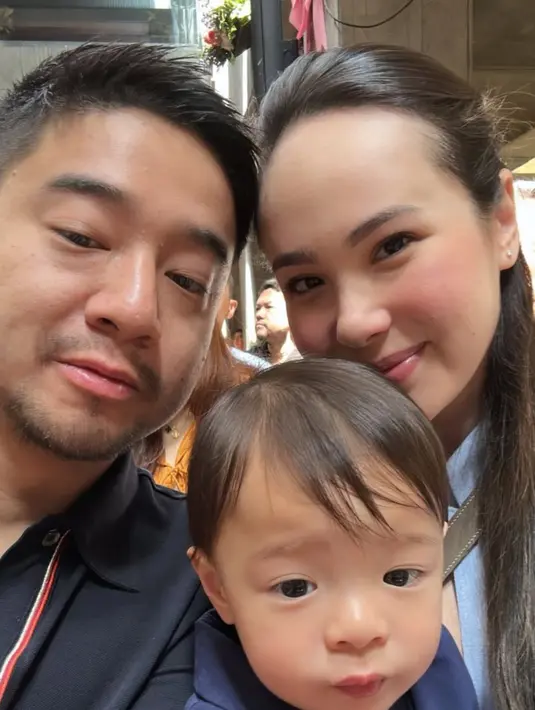 Pamela Bowie mengunggah potret selfie bersama suami dan putranya. Ia tampil dengan baju baby blue dengan riasan flawlessnya. [@pammybowie]