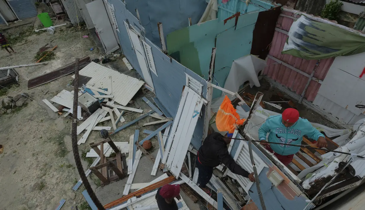 Warga mengganti atap rumah yang robek akibat Badai Fiona di lingkungan berpenghasilan rendah Kosovo di Veron de Punta Cana, Republik Dominika (19/9/2022). National Hurricane Center (NHC) yang berbasis di Miami mengatatakan bahwa Badai Fiona yang menghantam Republik Dominika itu termasuk dalam badai kategori 2, dengan kecepatan angin maksimum 110 mph. (AP Photo/Ricardo Hernandez)
