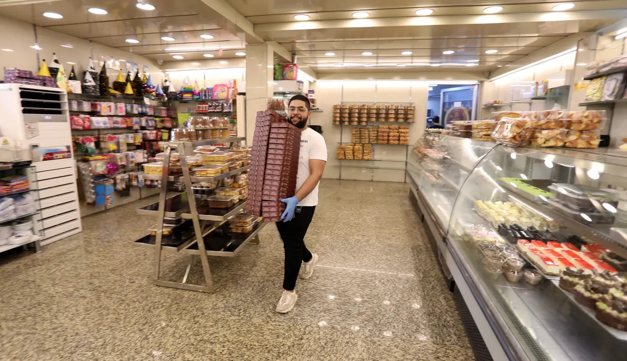 Seorang pekerja membawa sejumlah boks untuk penganan manis saat bulan suci Ramadan di sebuah toko di Baghdad, Irak, pada 3 Mei 2020. (Xinhua/Khalil Dawood)