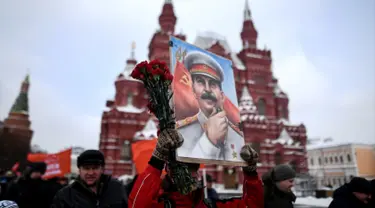 Seorang wanita membawa lukisan potret Stalin saat menghadiri upacara memperingati 65 tahun kematian pemimpin Uni Soviet Joseph Stalin di Lapangan Merah, Moskow (5/3). Stalin meninggal pada tahun 1924. (AFP/Kirill Kudryavtsev)