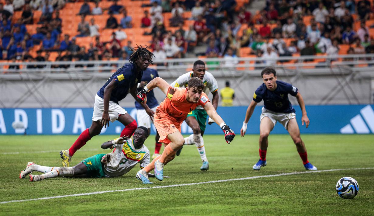 Kiper Timnas Prancis U-17, Paul Argney berusaha mengejar bola dari ancaman pemain Timnas Senegal U-17 pada laga babak 16 besar Piala Dunia U-17 di Jakarta International Stadium, Jakarta Utara, Rabu (22/22/2023) malam WIB. (Bola.com/Bagaskara Lazuardi)