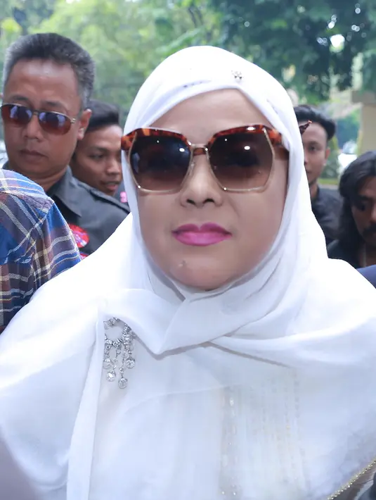 Ibunda Sandy tumiwa dalam balutan busana putih tak mengucapkan sepatah kata pun saat  tiba di Direktorat Reserse Kriminal Umum (Direskrimum). Diam seribu bahasa, ia berjalan terus dan masuk ke dalam gedung. (Galih W. Satria/Bintang.com)