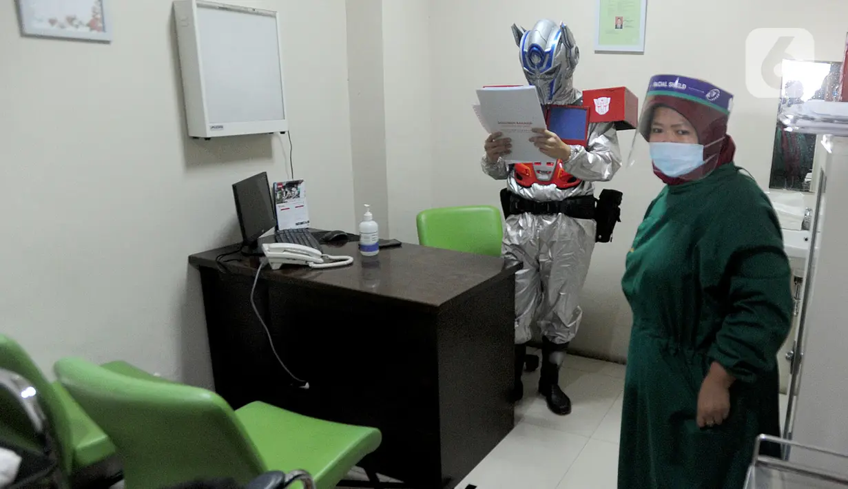 Dokter Rollando Erric Manibuy SpOT mengenakan alat pelindung diri (APD) ala transformer saat berada di RS Vania, Bogor, Jawa Barat, Jumat (22/5/2020). Penggunaan APD unik sejak merebaknya COVID-19 tersebut agar pasien tetap optimis meski sedang dalam pandemi. (merdeka.com/Arie Basuki)