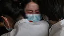 Staf medis dari Provinsi Jilin (tengah) memeluk perawat dari Wuhan setelah bekerja bersama menangani pandemi Covid-19 saat upacara pelepasan di Bandara Tianhe, Wuhan, provinsi Hubei, Rabu (8/4/2020). Pemulangan staf medis ini bersamaan dengan dicabutnya status lockdown Wuhan. (Hector RETAMAL/AFP)