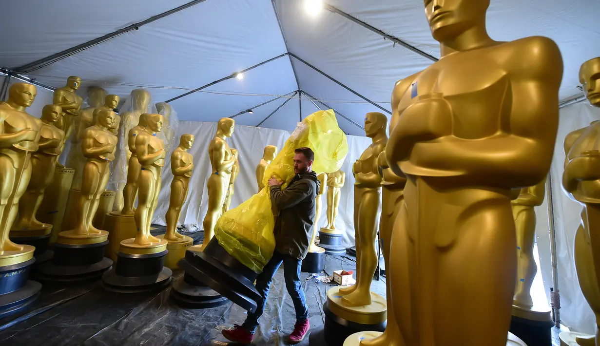 Pekerja membawa patung Oscar yang masih terbungkus untuk diberi sentuhan terakhir oleh seniman di Hollywood, California, 21 Februari 2017. Penganugerahan Academy Awards ke-89 akan diselenggarakan pada Minggu (26/2) waktu setempat. (Frederic J. Brown/AFP)