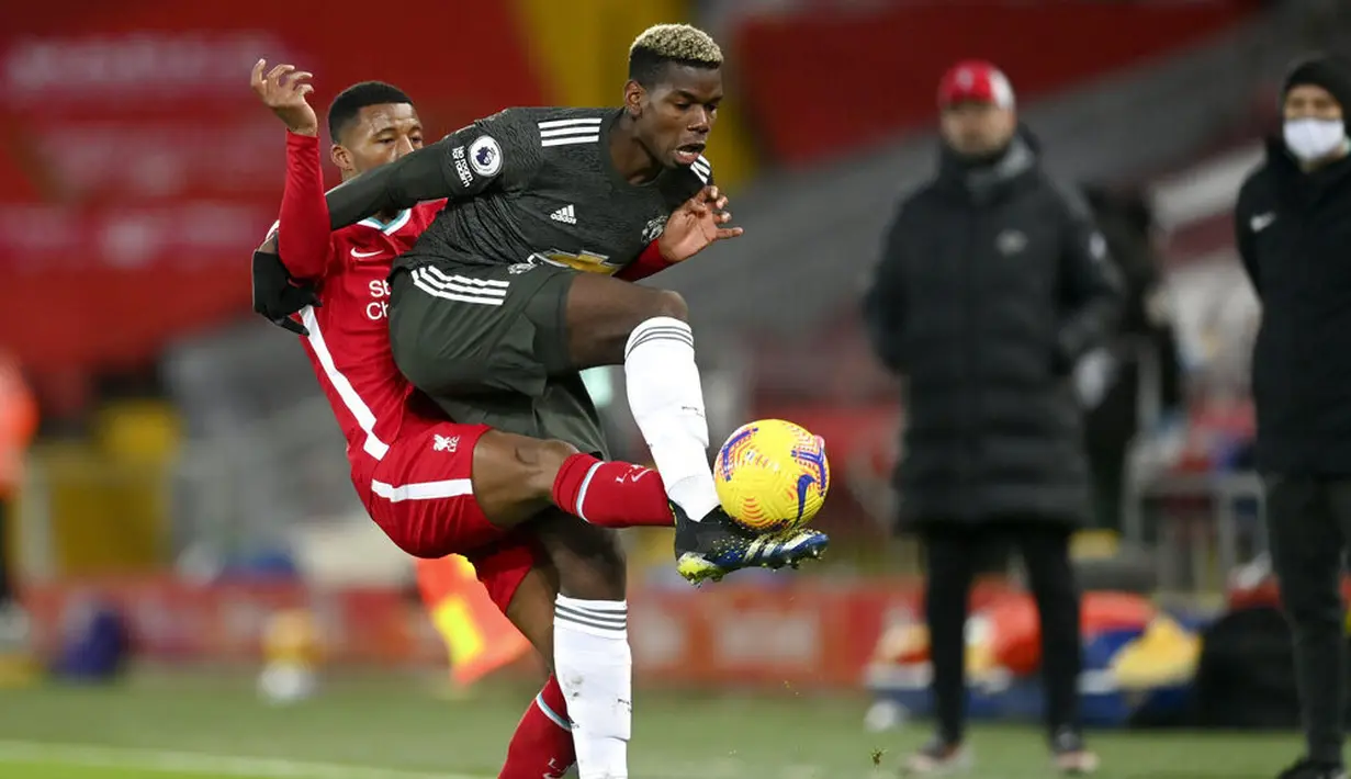 Pemain Manchester United, Paul Pogba, berebut bola dengan pemain Liverpool, Georginio Wijnaldum, pada laga Liga Inggris di Stadion Anfield, Minggu (17/1/2021). Kedua tim bermain imbang 0-0. (Michael Regan/Pool via AP)